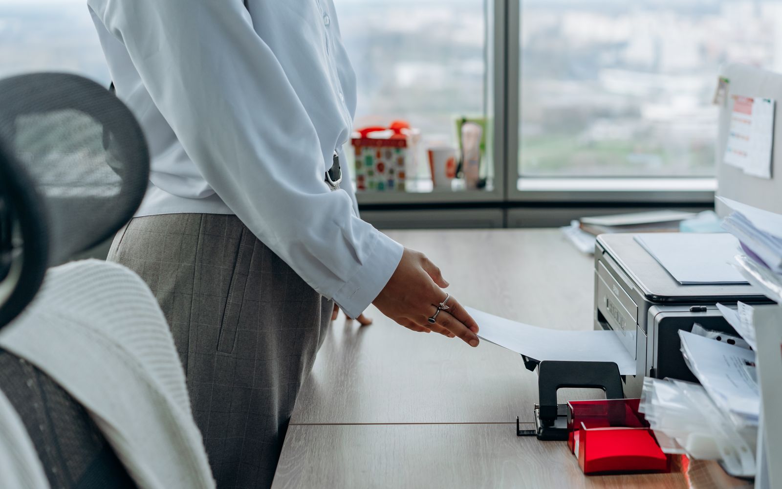 Business professional printing a document in an office environment.