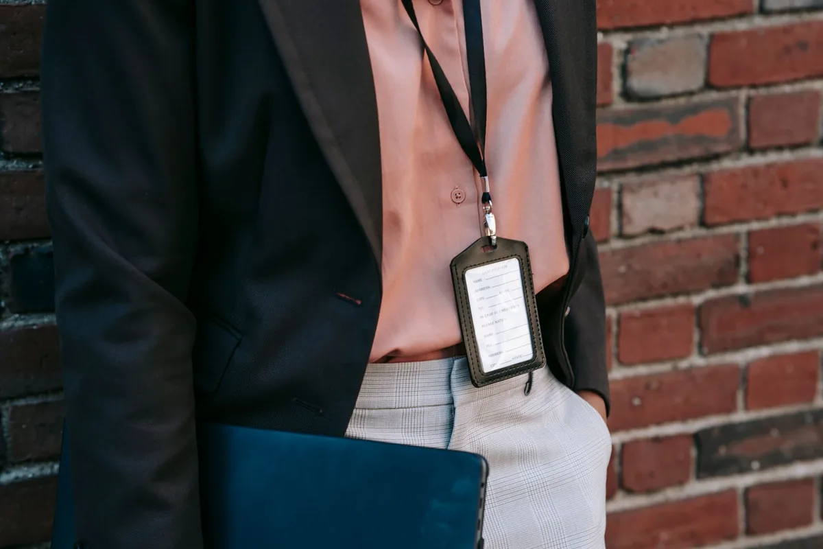 A printed ID badge worn in a clear holder on a lanyard.