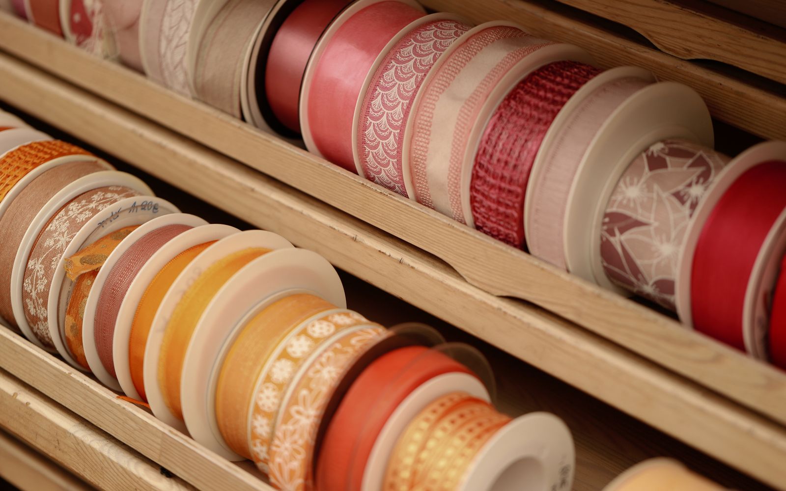 A vibrant collection of decorative ribbons neatly organized in a wooden display.