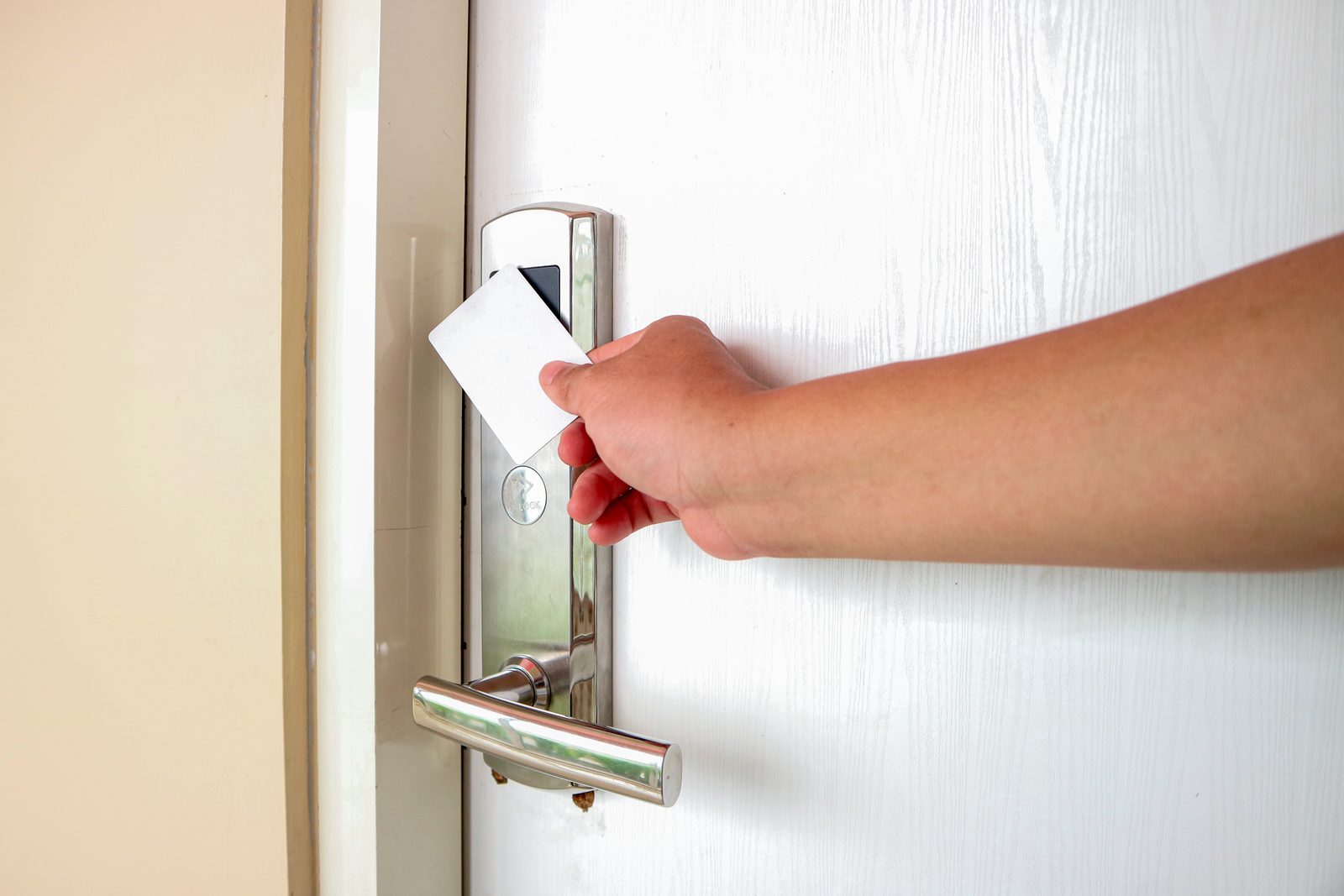 Hand holding an access key card at an electronic door