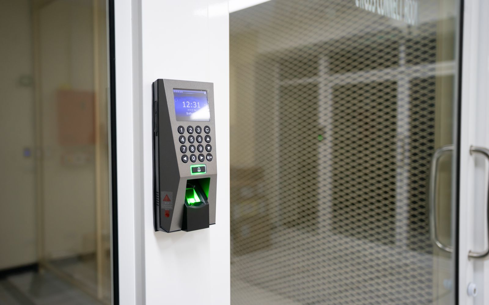 A wall-mounted access control reader beside a glass office door