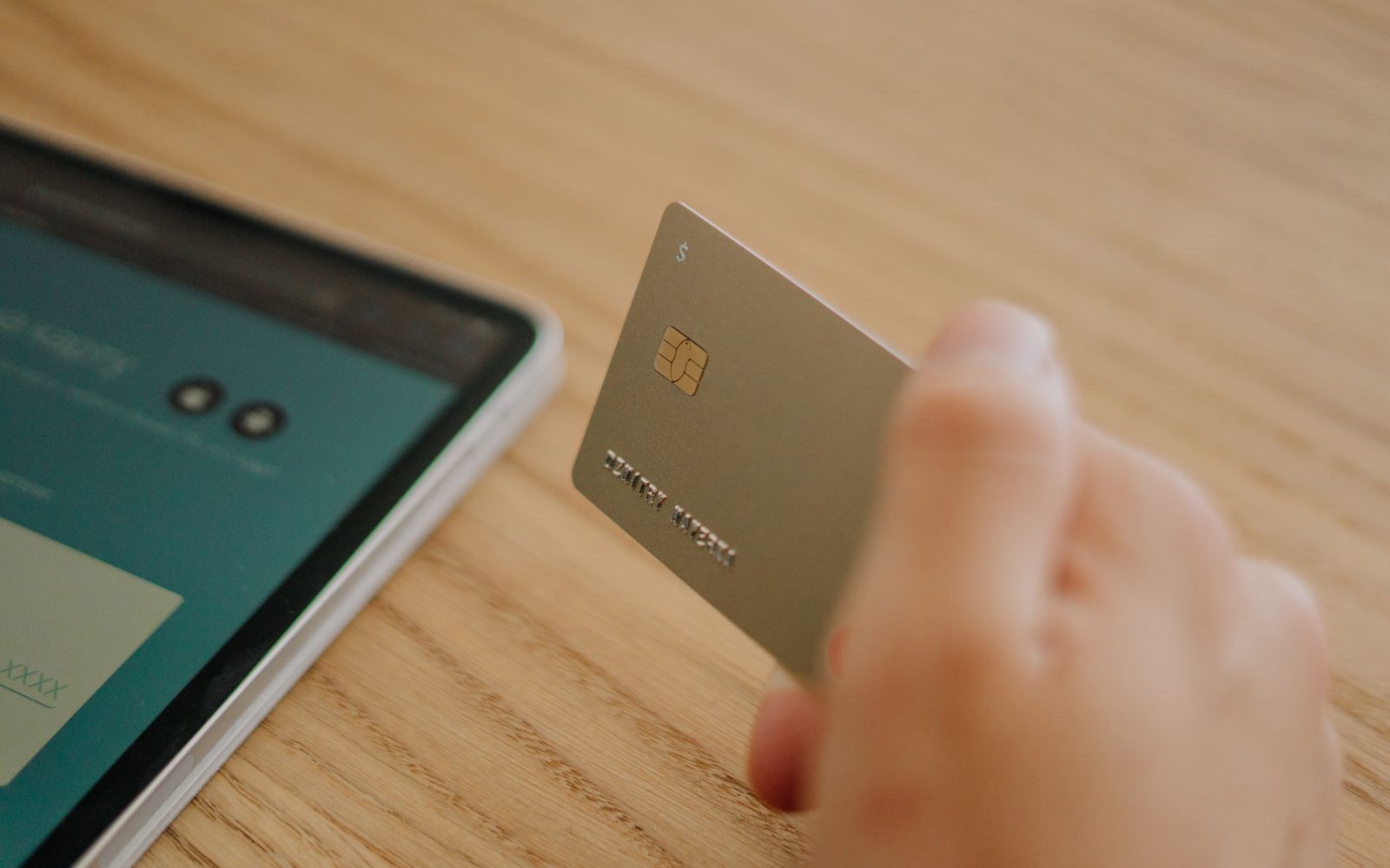 A smart card showing its gold contact chip, held over a desk