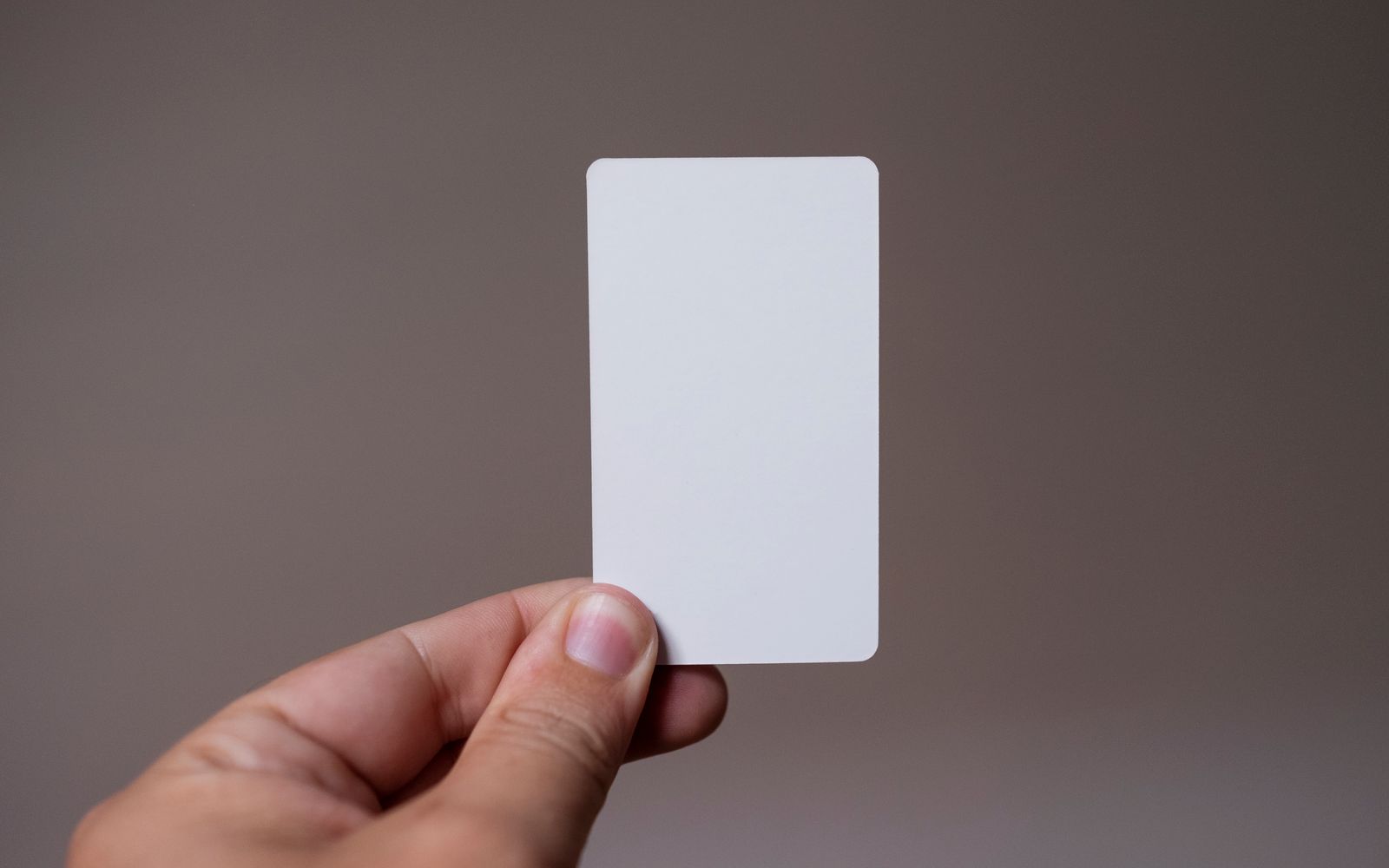 A blank white PVC card held up against a plain background